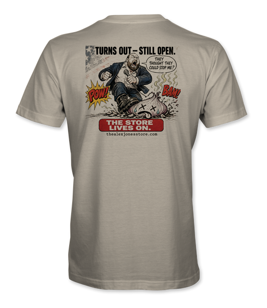 The Alex Jones Store - Back of cream Turns Out Still Open tee with Alex Jones stomping NPC onion comic art and 'The Store Lives On' banner
