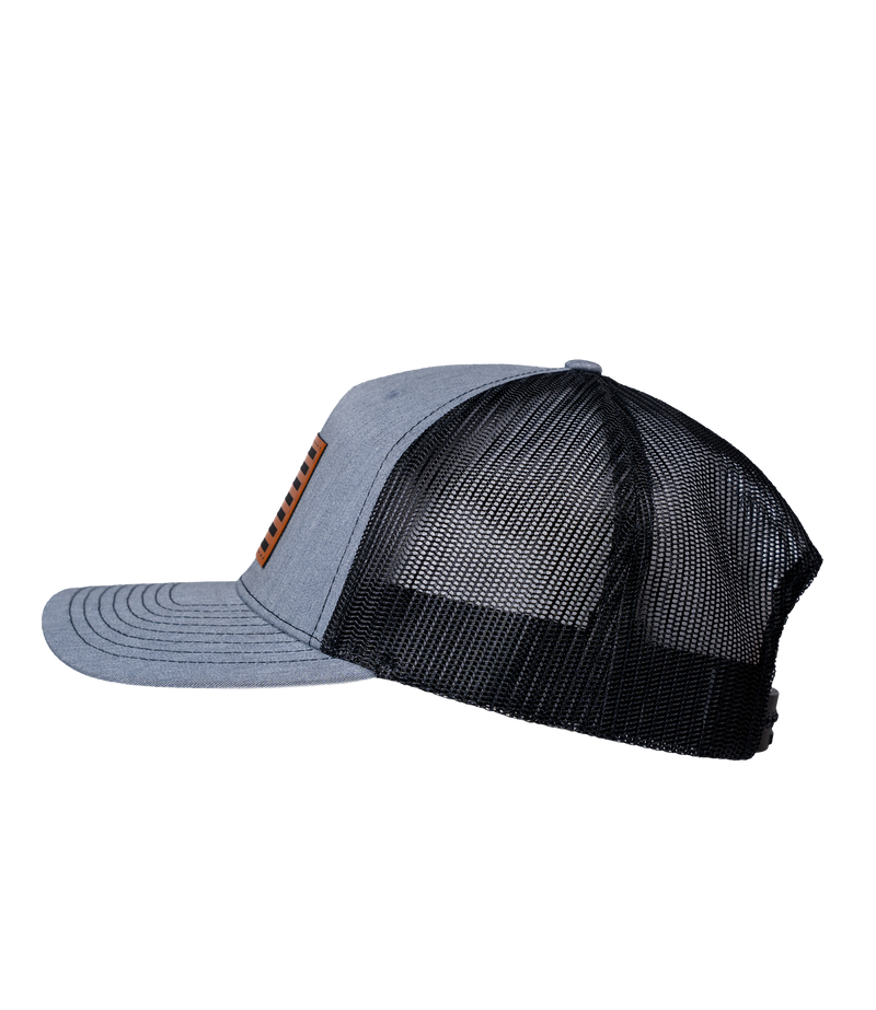 The Alex Jones Store - Heather grey and black trucker hat, left side view, with American flag leather patch on front, Betsy Ross flag style