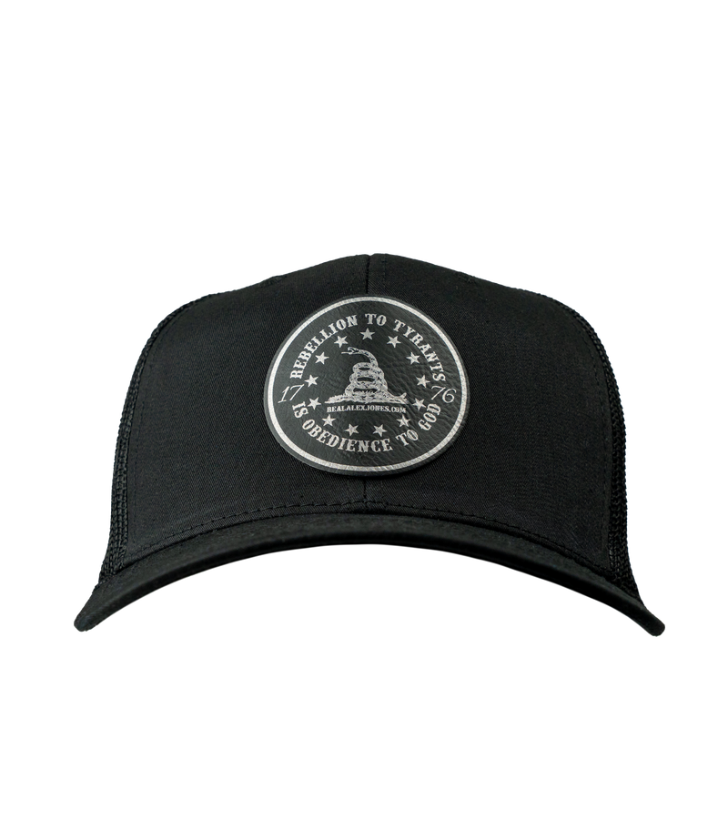 The Alex Jones Store - Front of black trucker hat with circular leather patch reading 'Rebellion To Tyrants Is Obedience To God' with Gadsden snake