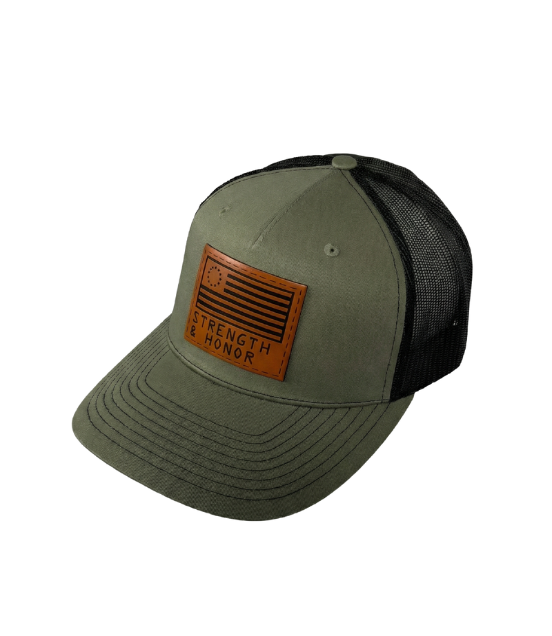 The Alex Jones Store - Angled view of olive green Strength & Honor leather patch trucker hat with black mesh side panels and curved brim