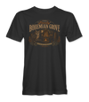 The Alex Jones Store - black Bohemian Grove t-shirt with a vintage travel label reading VISIT Lovely BOHEMIAN GROVE over an owl, a bonfire and TRADITION REQUIRES SACRIFICE