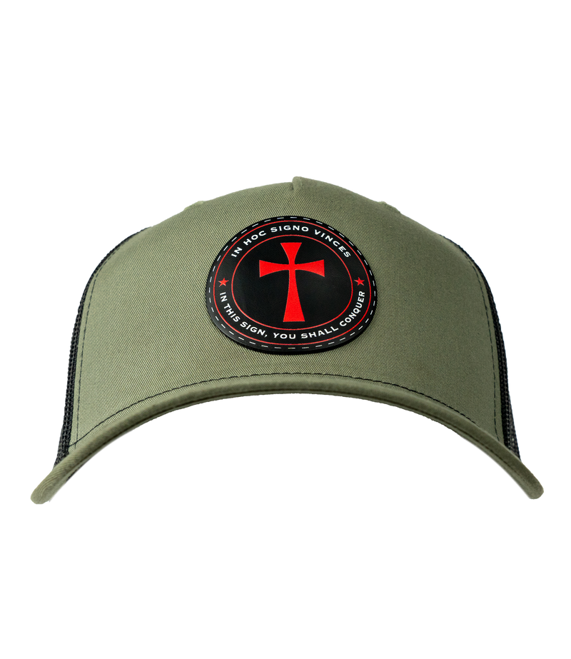 The Alex Jones Store - Front of olive green trucker hat with circular patch showing red cross and 'In Hoc Signo Vinces - In This Sign You Shall Conquer'