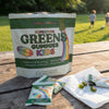 Kids Greens Gummies bag and open pouch of gummies on a picnic table