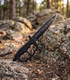 The Alex Jones Store - Don't Tread On Me Trench War Dagger with black knuckle-guard handle staged in pine forest on mossy rocks