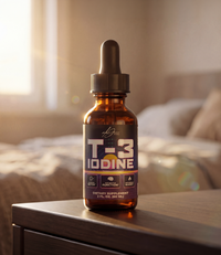 Alex Jones Naturals - T-3 Trifecta Iodine Tincture (90 Servings) — Amber T-3 Iodine dropper bottle on a wooden nightstand beside a bed with warm golden hour light streaming through window