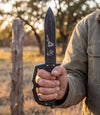 The Alex Jones Store - Life Is Fiery With It's Beauty Trench War Dagger held in hand at a Texas ranch fence line